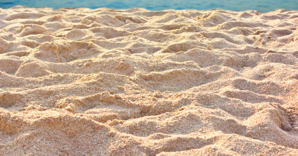 a photo focused on sand with water in the background