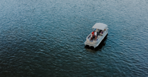 Pontoon Boat in  a body of water with people aboard.
